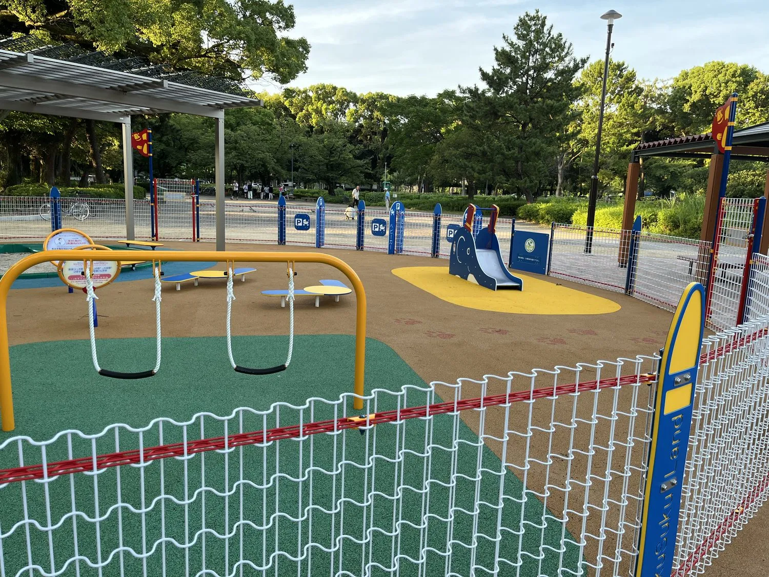 柵の外側に等間隔で並ぶ、Pマークとベビーカーの絵が描かれた青い標識。「ベビーカー」の文字も見える
