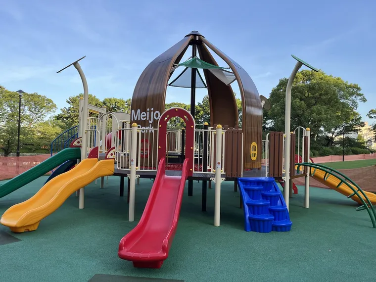 名城公園の子どもの広場にある大型遊具。茶色いドーム状の屋根に「Meijo Park」の文字、緑・黄・赤の3本の滑り台が並ぶ
